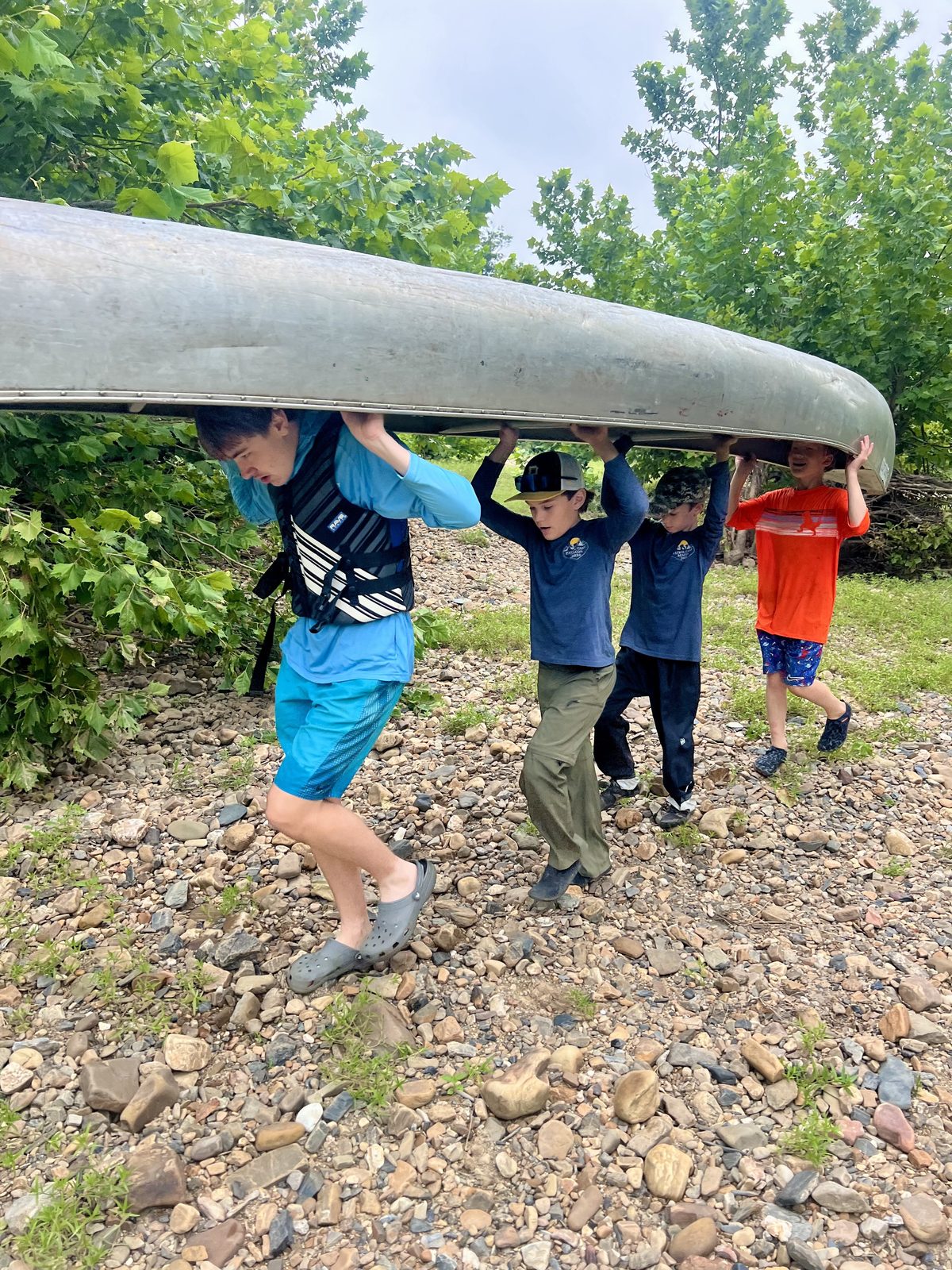 Trailmen portaging canoes along the riverbank